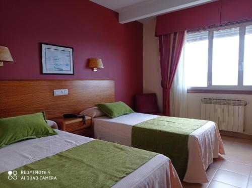 a hotel room with two beds and a window at Hotel Siroco Portonovo in Sanxenxo