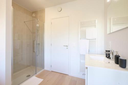 ein weißes Bad mit einer Dusche und einem Waschbecken in der Unterkunft Lumineux Appartement 1 chambre proche Ecole Européenne in Brüssel