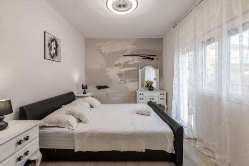 a white bedroom with a bed and a window at Mala Kate Apartments in Kaštela
