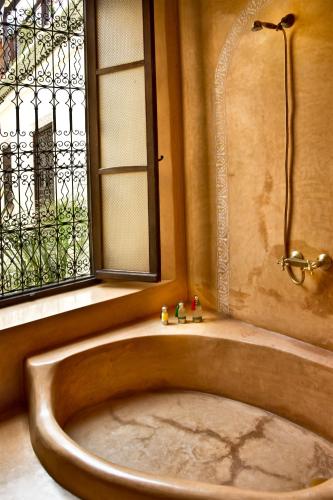 a bath tub in a bathroom with a window at Riad Al Loune in Marrakech