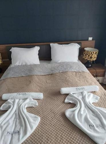 a bed with two white towels on top of it at Deluxe Apartments Приморско in Primorsko