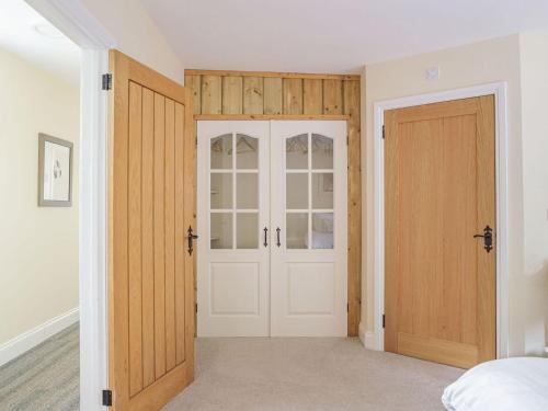 a bedroom with white walls and wooden doors at Chapel Barn in Bolnhurst