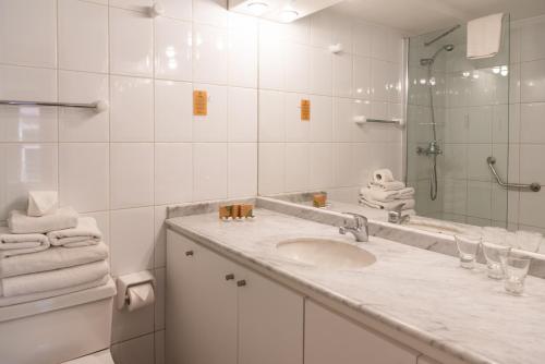 a white bathroom with a sink and a mirror at MR Apart Providencia (ex Apart Neruda) in Santiago