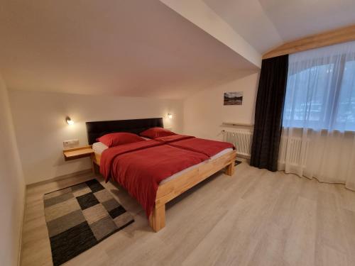 a bedroom with a red bed and a window at Ferienwohnungen Paar in Schönau am Königssee