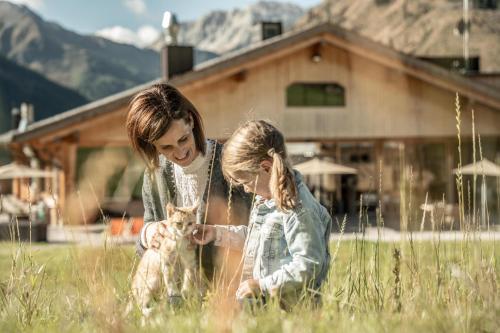 a woman and a little girl playing with a cat at Almfamilyhotel Scherer in Obertilliach