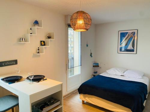 une chambre avec un lit, une table et un bureau dans l'établissement Charmant Studio Front de Mer, à Cabourg
