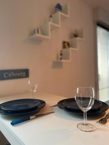 - une table avec deux assiettes et des verres à vin dans l'établissement Charmant Studio Front de Mer, à Cabourg