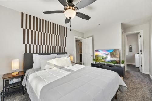 a bedroom with a white bed and a ceiling fan at Peaceful Home w/ 4BR, Big Yard and amazing art in Denver