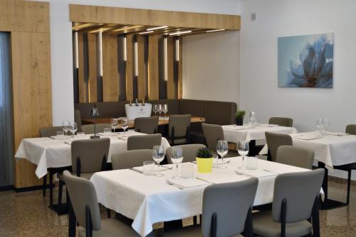 un restaurante con mesas blancas y sillas con copas de vino en Albergo Ristorante Da Neni, en Mori
