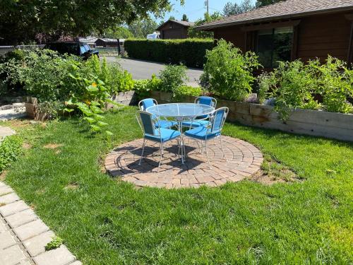 a glass table and two blue chairs on a brick patio at DunMovin’ Oregon in Grants Pass