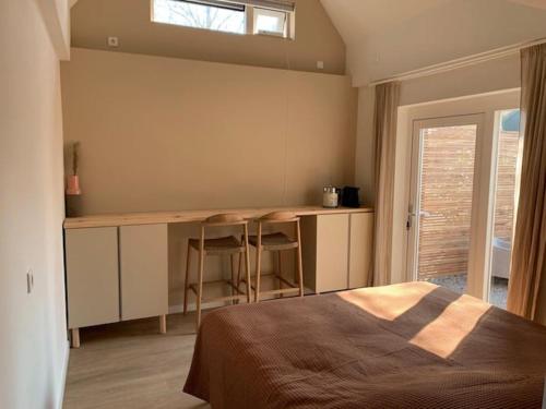 a bedroom with a bed and a desk and a window at Guest room with terrace at the Wadden Sea in Oosterend