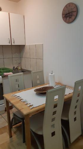 a kitchen with a wooden table with chairs and a clock at Sirmijum Hause in Sremska Mitrovica