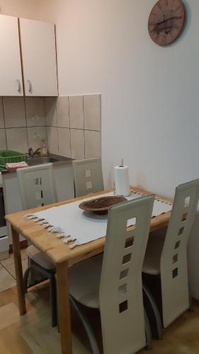 cocina con mesa de madera con sillas y reloj en Sirmijum Hause, en Sremska Mitrovica