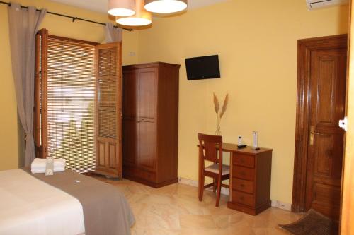 a bedroom with a bed and a desk and a tv at Hotel La Zubia , Granada in La Zubia