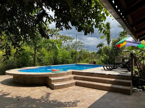 una piscina con banco y sombrilla en QUINTA VACACIONAL DIEGO ALFONSO, MY house in Macas en Macas