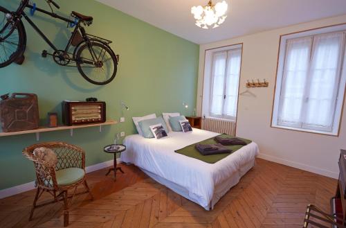 a bedroom with a bed with a bike hanging on the wall at Normand'Histoire Chambres d'Hôtes in Isigny-sur-Mer