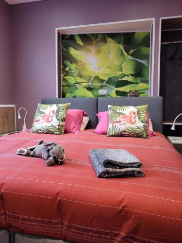 a stuffed animal laying on top of a red bed at Le Relais De L'Aube in Villers-Bretonneux