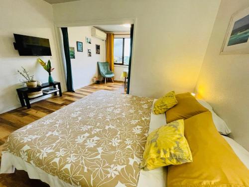 Un dormitorio con una cama con almohadas amarillas. en Studio Hina - Cosy, Quiet & Pool, en Papeete