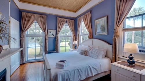 a bedroom with a white bed with blue walls and windows at Forsyth Park 2 Bedroom Beauty in Savannah
