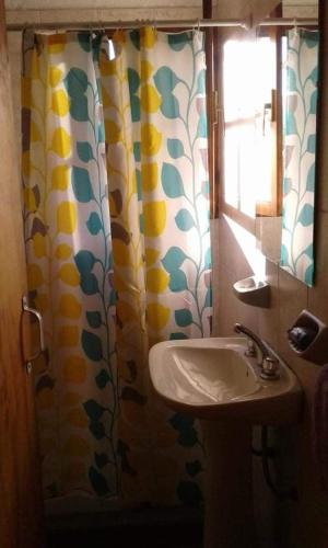 baño con lavabo y cortina de ducha en Cabaña Fuego Interior en El Bolsón