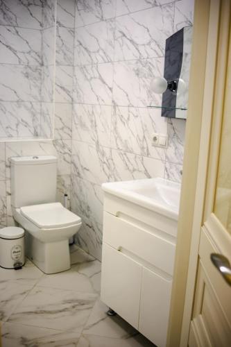a white bathroom with a toilet and a sink at Вілла Aqua Shayan in Shaian