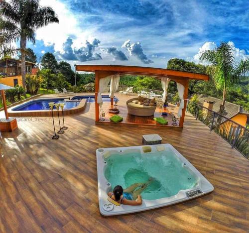 a woman laying in a hot tub on a deck at Carícia do Vento Pousada Boutique in Monte Verde