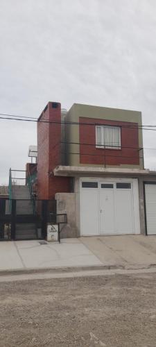ein Gebäude mit zwei weißen Garagentüren auf einer Straße in der Unterkunft Departamento América in Puerto Madryn