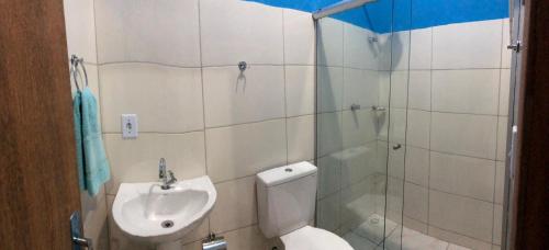 a bathroom with a shower and a toilet and a sink at Pousada Flor de Laranjeira in Lençóis