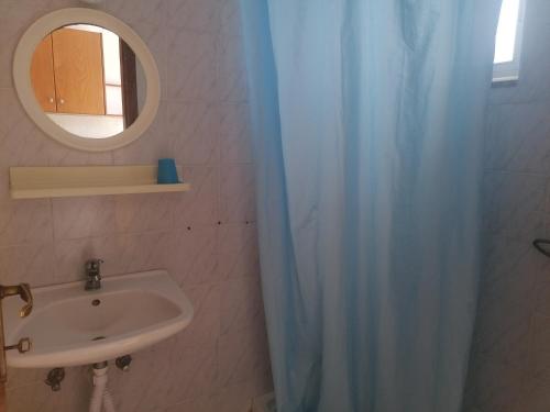 łazienka z zasłoną prysznicową i umywalką w obiekcie Kefalos Studios Stamatia w mieście Kefalos