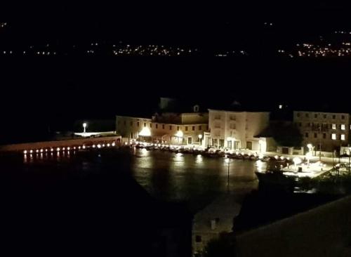 a night view of a building with lights in the water at Apartments Ita - Postira in Postira