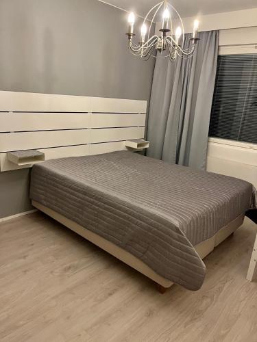 a bedroom with a large bed and a chandelier at 4 km to the Jyväskylä city center afoot, cute apartment with free parking in Jyväskylä