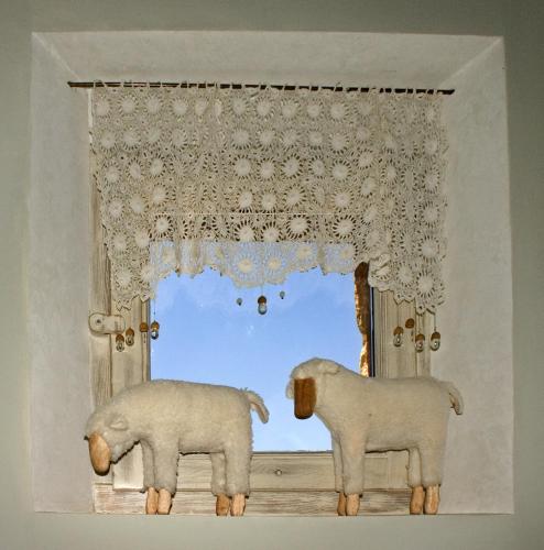 two sheep standing in a window with a curtain at Alodia in Alquézar
