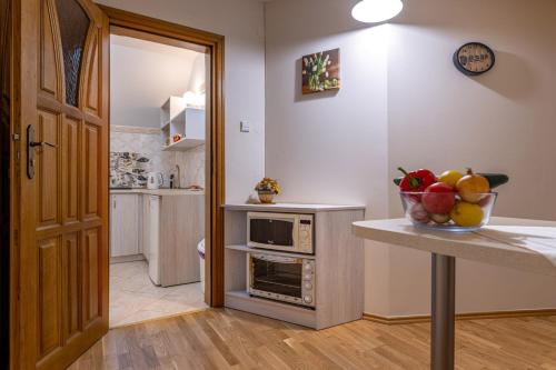 a kitchen with a counter with a bowl of fruit on a table at Pensjonat nad Płaskim in Jerzwałd