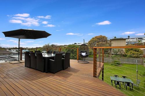 a wooden deck with a table and an umbrella at Family Retreat 500m to the beach in Ocean Grove