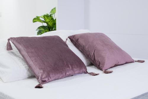 dos almohadas moradas sentadas encima de una cama en Estudio Playa Los Locos, Torrevieja, en Torrevieja
