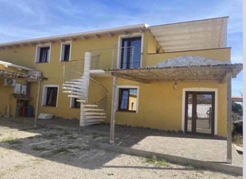 una casa amarilla con una escalera delante de ella en IL TRAMONTO, en SantʼAnna Arresi