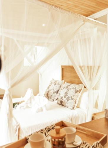 a bedroom with a bed with white drapes at Baluleni Safari Lodge in Grietjie Nature Reserve