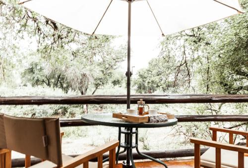 a table and chairs in front of a window at Baluleni Safari Lodge in Grietjie Nature Reserve