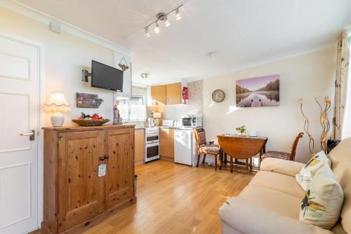 a living room with a couch and a kitchen at The Bee's Knees in Mundesley