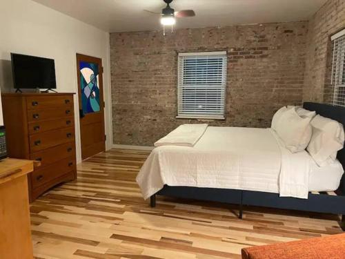 ein Schlafzimmer mit einem weißen Bett und einer Ziegelwand in der Unterkunft Brick Street Apartment-Studio Suite in Augusta
