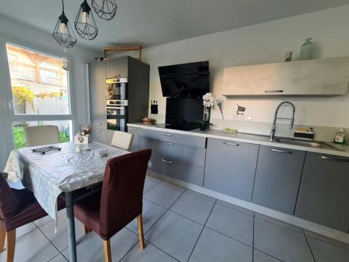 kuchnia ze stołem i krzesłami oraz kuchnia ze zlewem w obiekcie Joli Appartement vue montagne, cosy avec jardin w mieście Bonneville