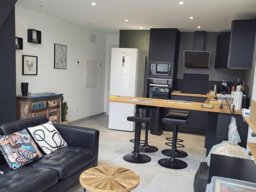 un salon avec un canapé et une cuisine avec un comptoir dans l'établissement Maison contemporaine 47m² proche plage, commerces, à Saint-Georges-de-Didonne