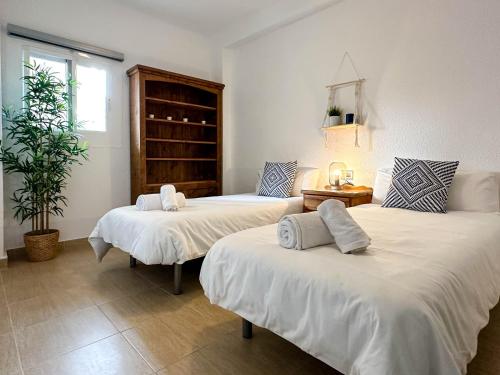 a bedroom with two beds with white sheets and a plant at Jardín Playa San Juan in Alicante