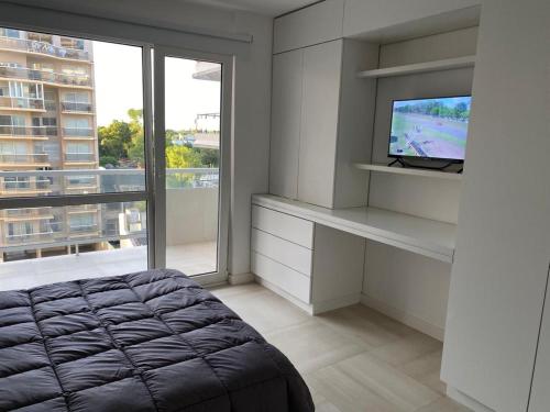 1 dormitorio con 1 cama, TV y ventana en EG10 en Mar del Plata