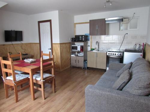 a living room with a couch and a table and a kitchen at Departamentos Kitkaika in Punta Arenas