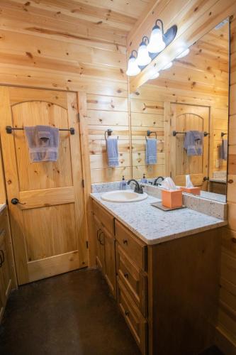a log cabin bathroom with a sink and a mirror at HochaHoma Luxury Cabin in Broken Bow