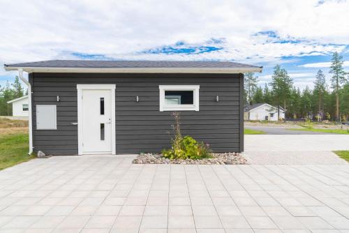 a small black shed with a white door at Guestly Homes - Seaside Stay with Sauna in Piteå