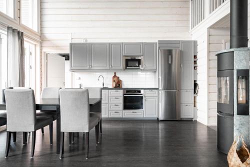 a kitchen with a table and chairs and a refrigerator at Guestly Homes - Seaside Stay with Sauna in Piteå