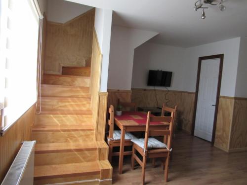 a dining room with a table and a room with stairs at Departamentos Kitkaika in Punta Arenas