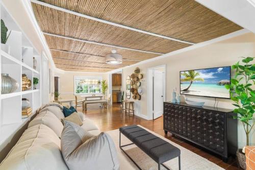 a living room with a couch and a tv on the wall at Tropical Oasis Located Near Lake With Pool and Hot Tub in West Palm Beach